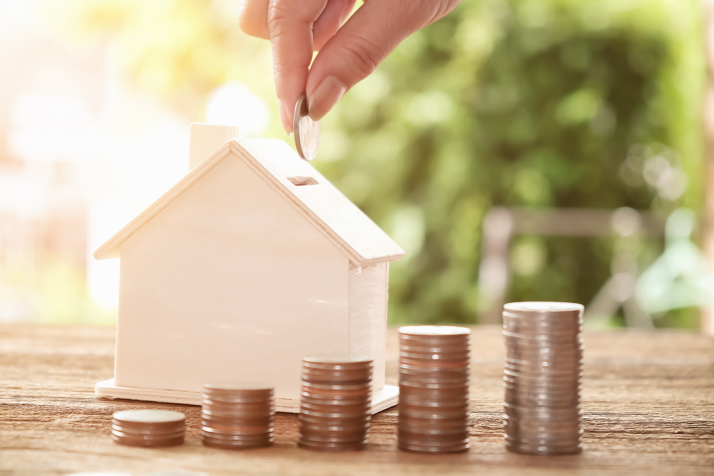 Person Putting a Coin in a House Bank